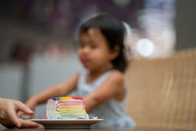 Close-up of food in plate against girl in background on table