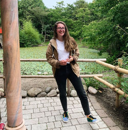 Full length portrait of smiling young woman outdoors