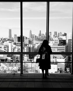 Full length of woman with arms raised against sky in city