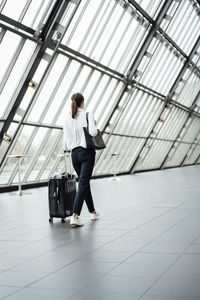 Female entrepreneur with suitcase walking in corridor of office