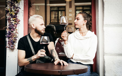 Young couple holding wineglass while sitting at cafe