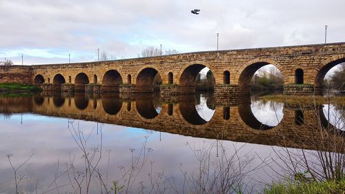 Arch bridge over river against sky