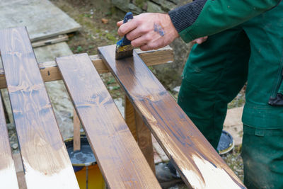 Midsection of man painting wooden plank