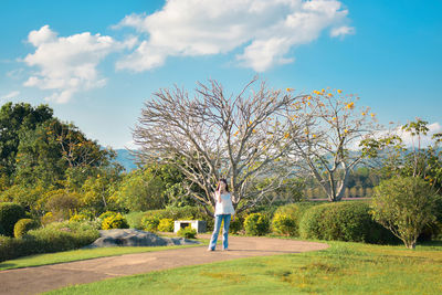 Rear view of woman standing on field against sky