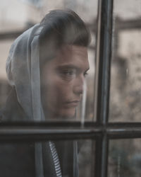 Portrait of young man looking through window