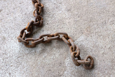 
top view an old chain rusted on the cement floor.