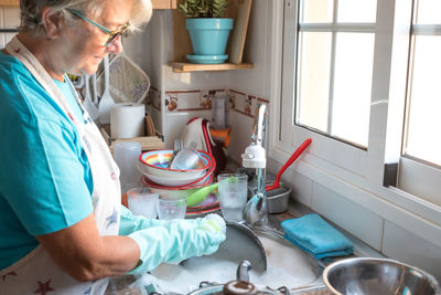 Side view of woman cleaning plate in sink