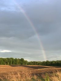 Scenic view of field against rainbow in sky