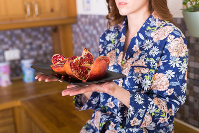 Midsection of woman holding pomegranate