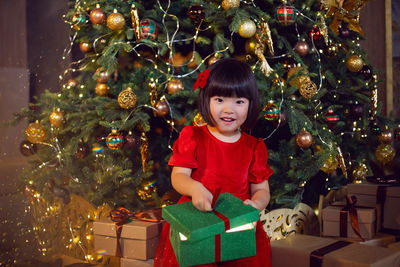 Portrait of a beautiful korean girl child in red dress at christmas with box of gifts christmas tree