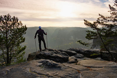 Lone hiker man with trekking poles enjoying peak mountain view during altitude acclimatization walk