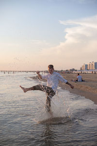 Man swimming in sea against sky during sunset