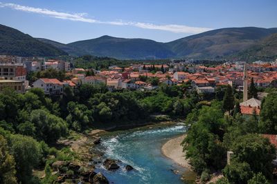 Town by river and mountains against blue sky