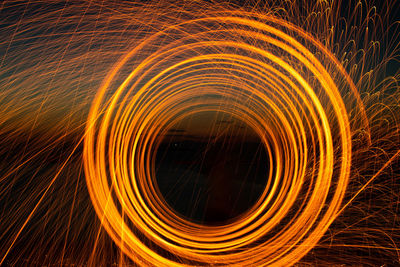 Spinning wire wool against sky at night