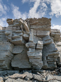 Low angle view of old rocks against cloudy sky