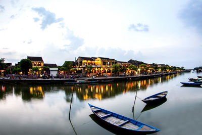 Boats moored on lake by buildings against sky