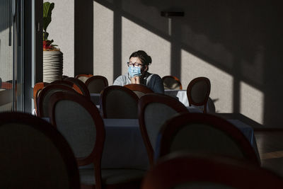 Woman wearing mask sitting at cafe