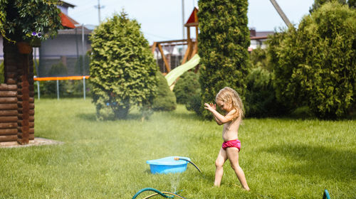 Little girl playing with water in the yard of the house