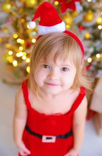 High angle portrait of cute girl standing by christmas decoration