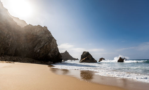 Isolated beautiful beach in afternoon sun, rocks and waves, atlantic ocean, praia da ursa, portugal