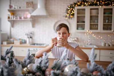 Thoughtful boy drinking coffee at home during christmas
