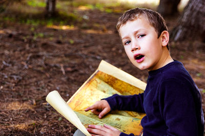 Portrait of boy holding map on land