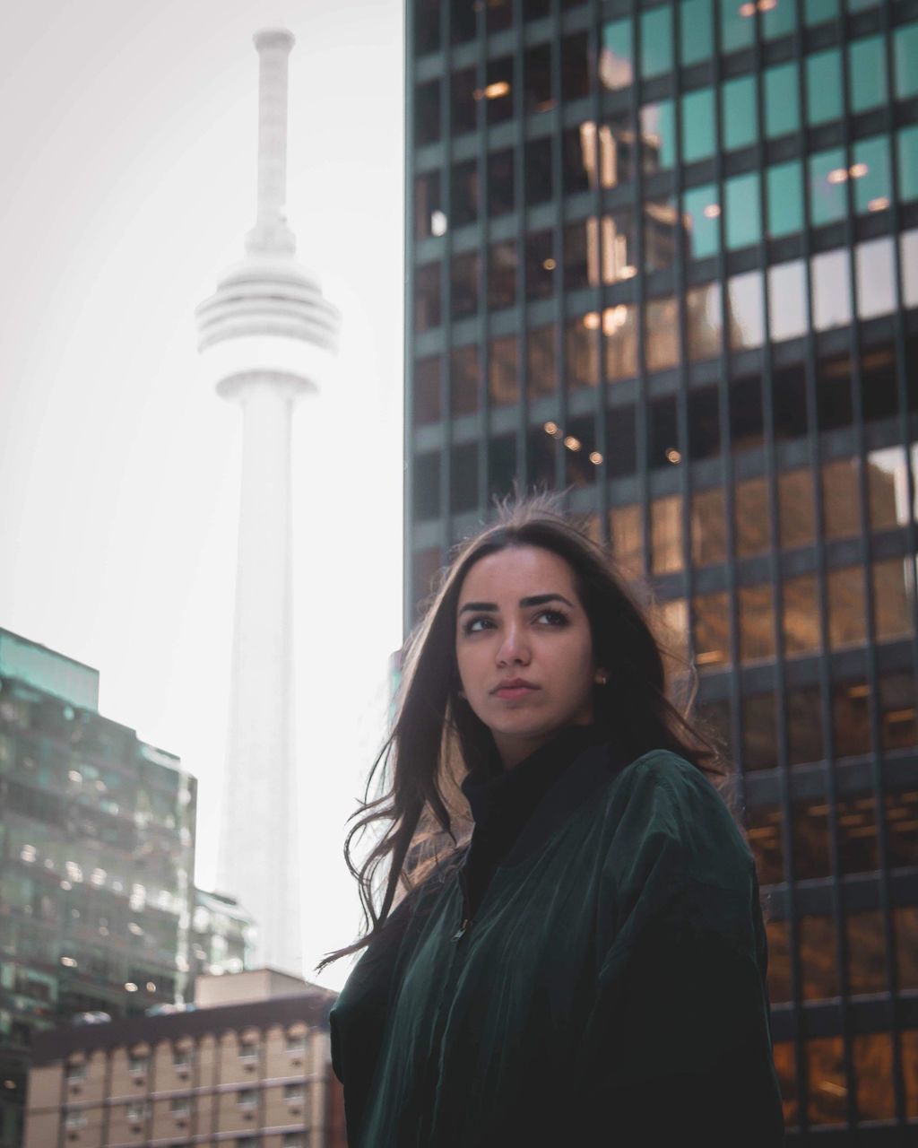 architecture, built structure, building exterior, one person, city, portrait, young adult, building, beauty, lifestyles, looking at camera, hair, real people, leisure activity, young women, tower, office building exterior, women, hairstyle, skyscraper, tall - high, beautiful woman, outdoors, modern