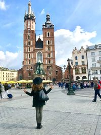 Woman walking in front of building against sky in city