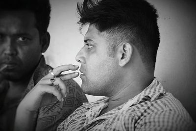 Close-up of thoughtful young man sitting against wall