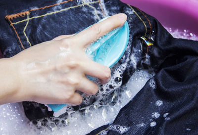 Cropped hand of woman washing jeans