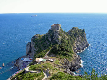 Historic building on rocks by sea against clear sky