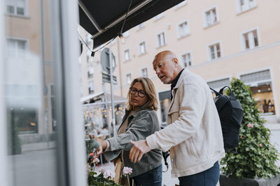 Male and female senior friends shopping together at street