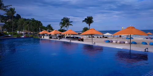 View of swimming pool by sea against blue sky