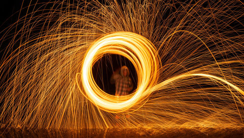Man spinning wire wool standing in water at night