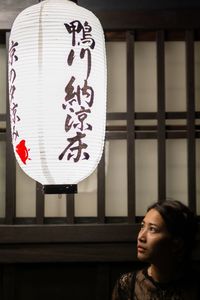 Young woman looking away by illuminated lantern