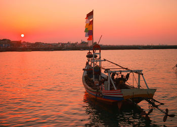 Ship moored in sea against sky during sunset