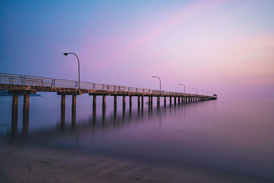 Pier over sea against sky during sunset