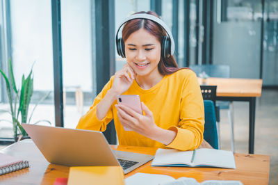 Portrait of young woman using laptop while sitting on table