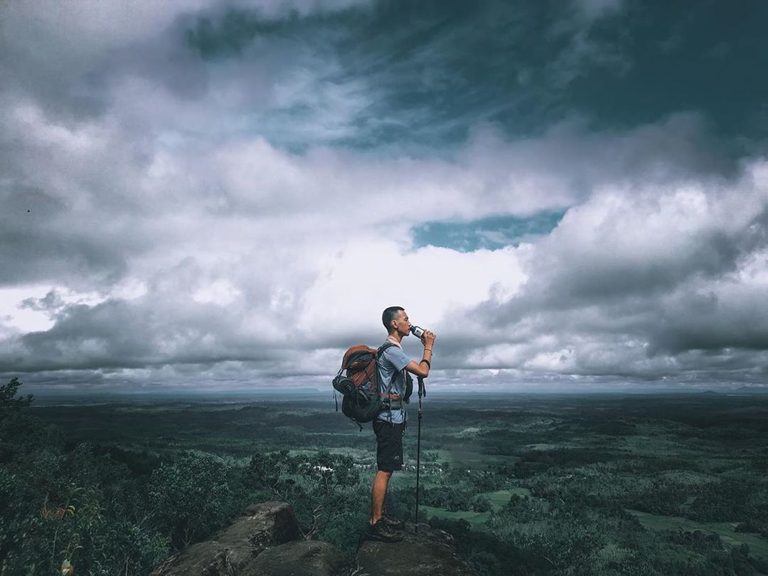 MAN STANDING ON LANDSCAPE AGAINST CLOUDY SKY