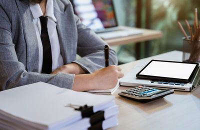 Midsection of woman using digital tablet at office