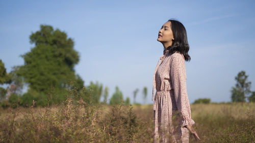 Side view of woman standing on field against sky