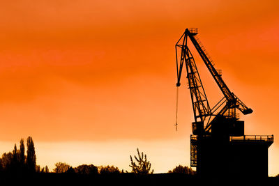 Low angle view of silhouette crane against sky during sunset