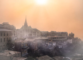 Buildings in city against sky during sunset