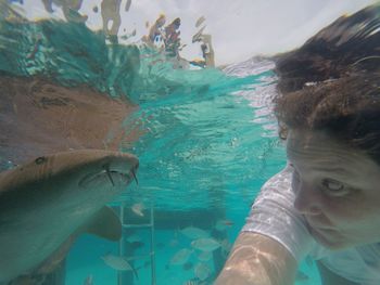 Close-up of young woman swimming by fish in pool