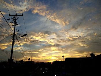 Low angle view of silhouette electricity pylon against sky during sunset