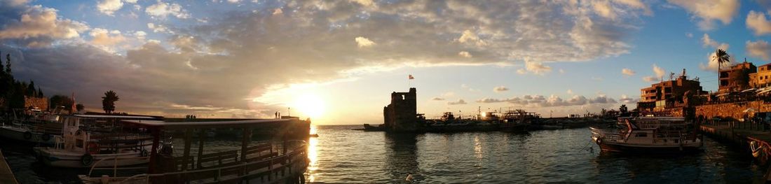 Boats in harbor against cloudy sky