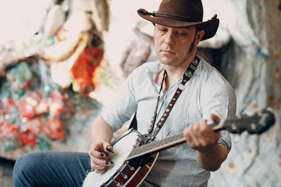 Man wearing hat playing guitar