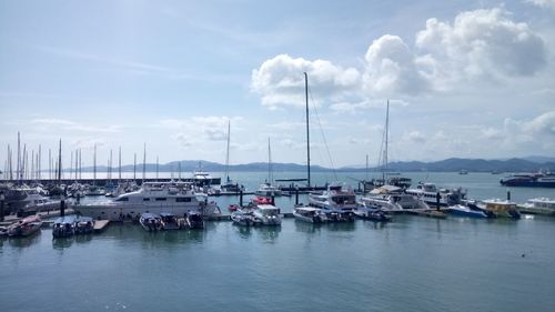 Sailboats moored in harbor against sky