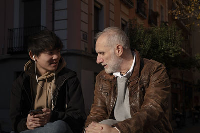 Asian teenage boy and caucasian adult man chatting on street. madrid. spain
