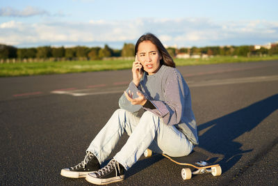 Portrait of young woman sitting on road